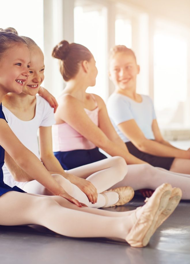 Little girls smiling and embracing in ballet class